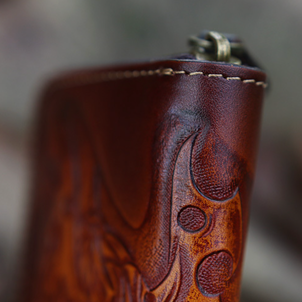 Close-up of a brown leather key pouch with intricate designs on a blurred background