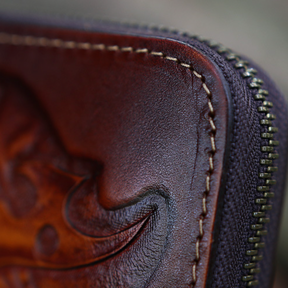 Close-up of a brown leather wallet with intricate stitching and embossed design.
