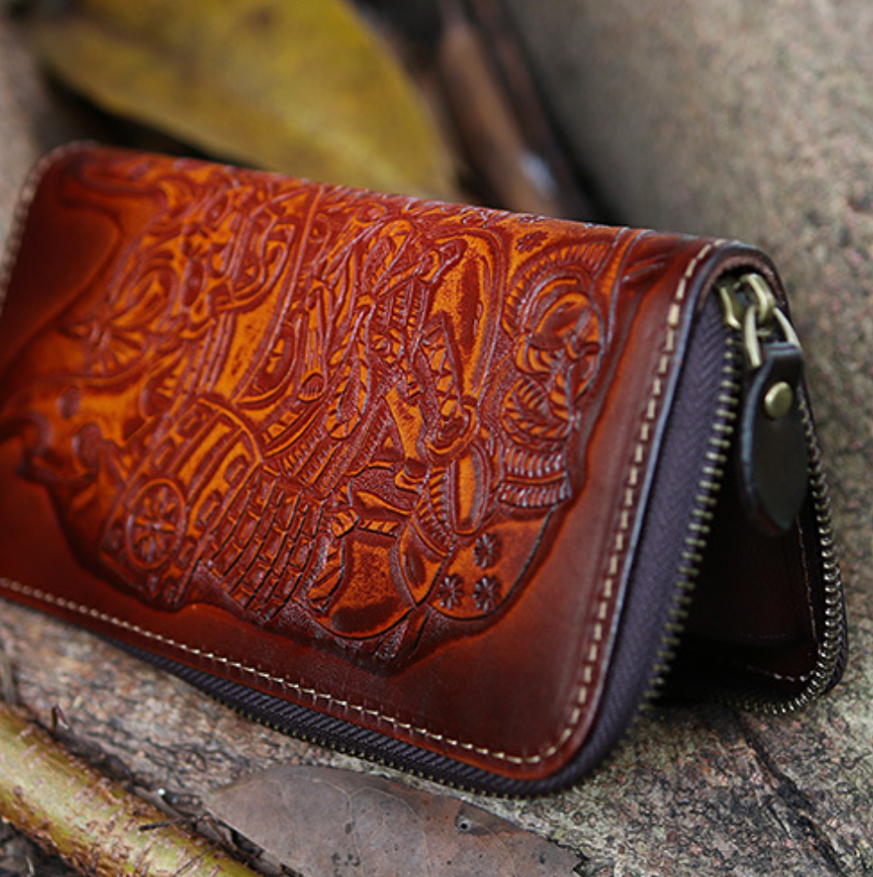 Brown leather wallet with intricate designs on a stone surface