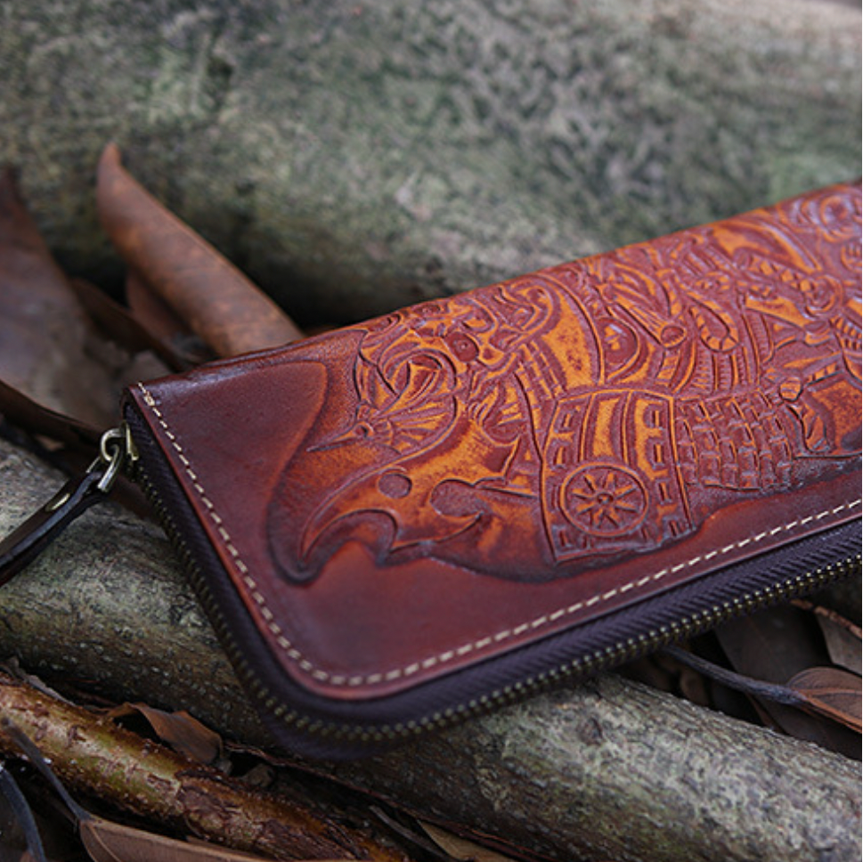 Brown leather wallet with intricate designs on a stone surface