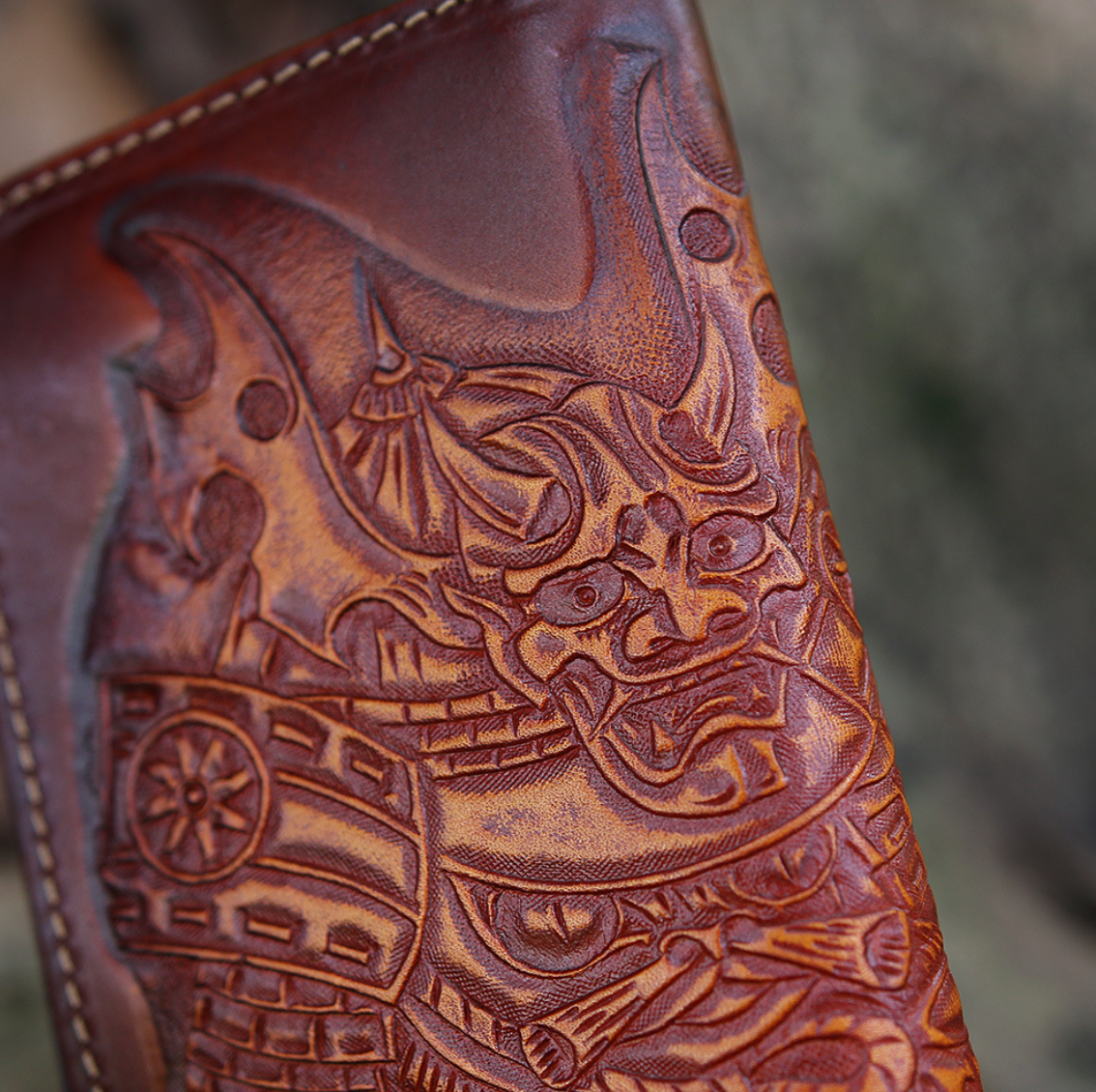 Close-up of a brown leather wallet with intricate embossed design on a blurred background