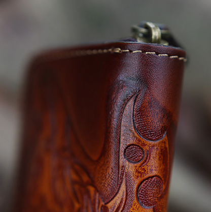 Close-up of a brown leather key pouch with intricate designs on a blurred background