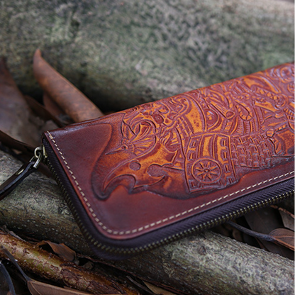 Brown leather wallet with intricate designs on a stone surface