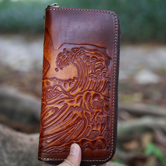 Brown leather wallet with embossed design held against a natural background